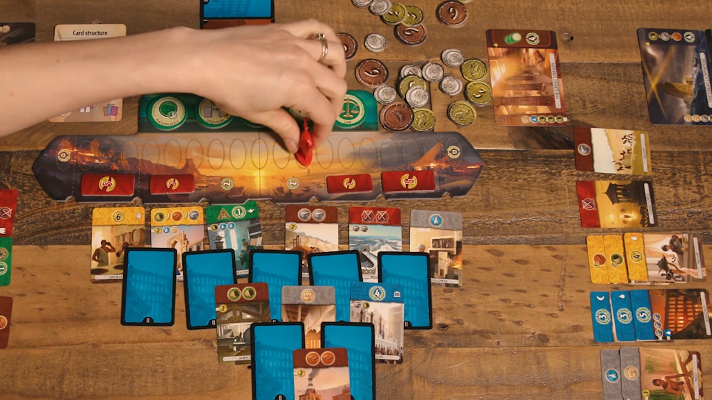 Tabla i karte društvene igre „7 Wonders Duel” sa žetonima i novčićima raspoređenim po stolu